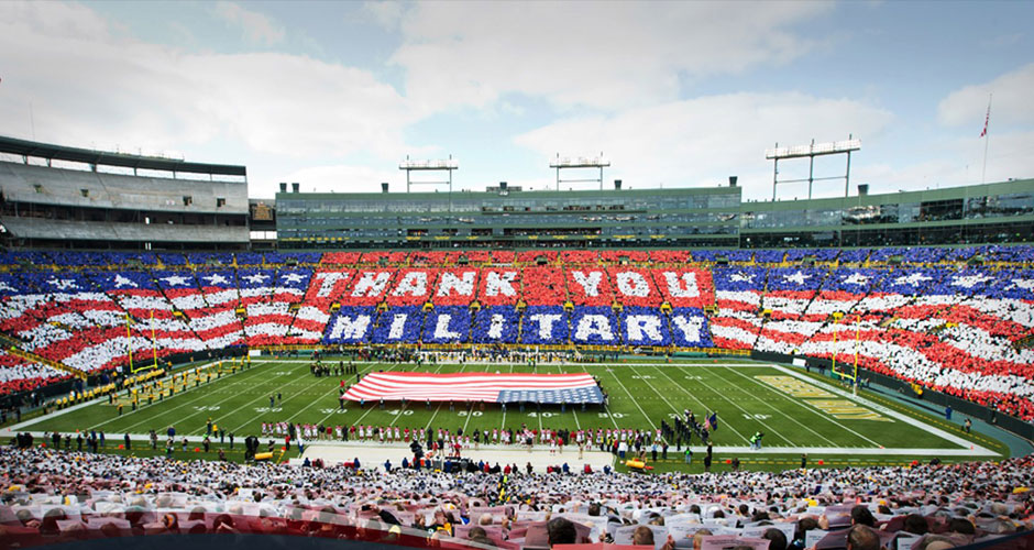 Image of a football stadium doing a card stunt thanking the military. 